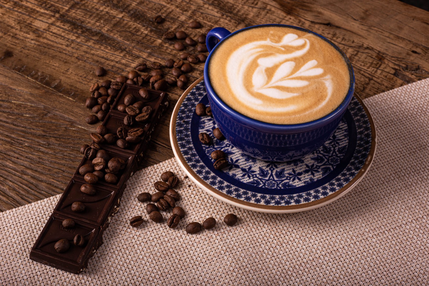 Une tasse de café accompagnée de chocolat noir et de grains de café